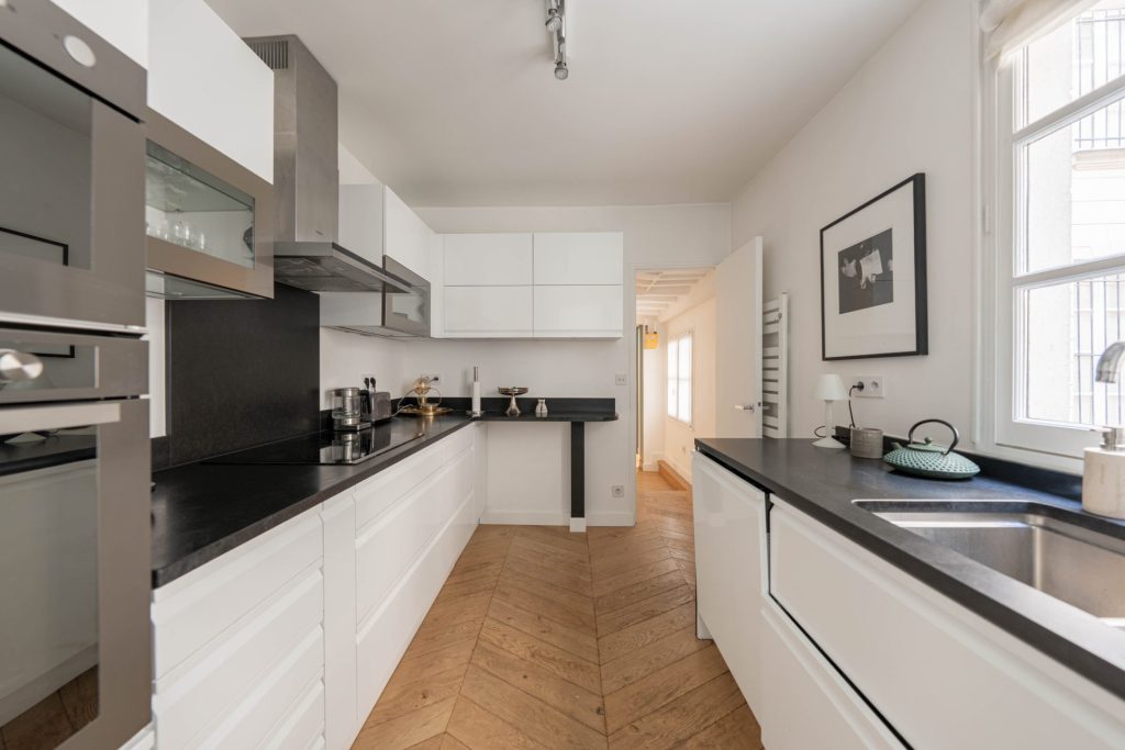 1 995 000 € - Paris 1er - Vendôme / Saint-Honoré - 114 m² with terrace Cuisine blanche et noire avec parquet point de Hongrie dans un appartement à Paris 1