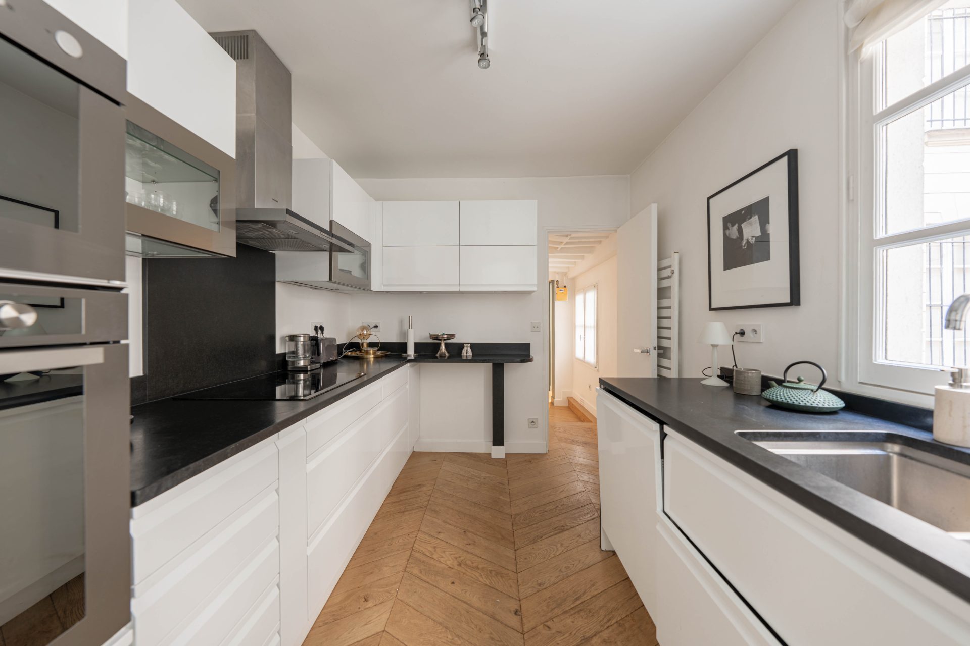 1 790 000 € - Paris 1er • Vendôme / Saint-Honoré • 114 m² avec terrasse Cuisine blanche et noire avec parquet point de Hongrie dans un appartement à Paris 1