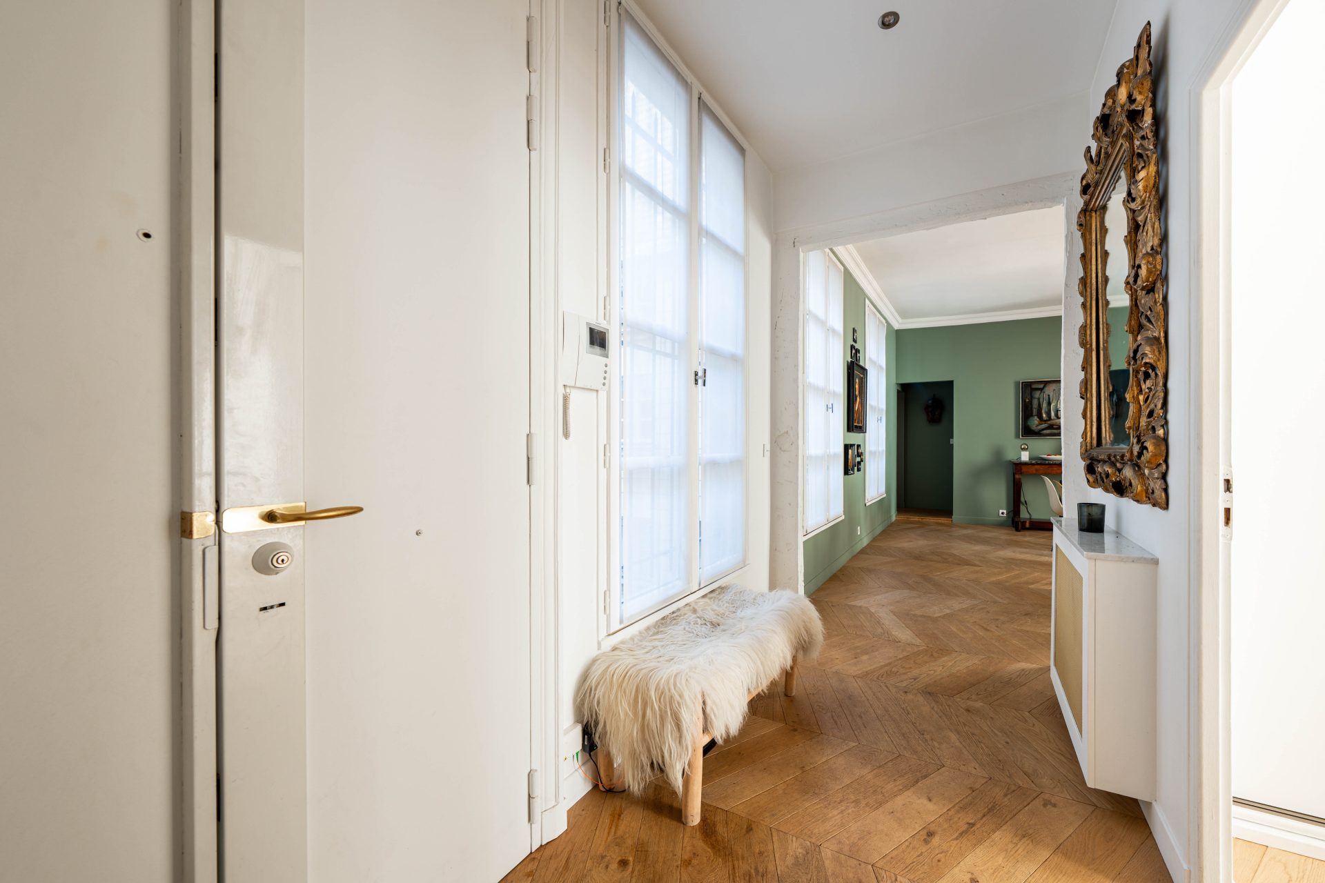1 790 000 € - Paris 1er • Vendôme / Saint-Honoré • 114 m² avec terrasse Entrée d’un appartement rénové à Paris 1 avec parquet en point de Hongrie, miroir ancien doré et perspective sur la salle à manger