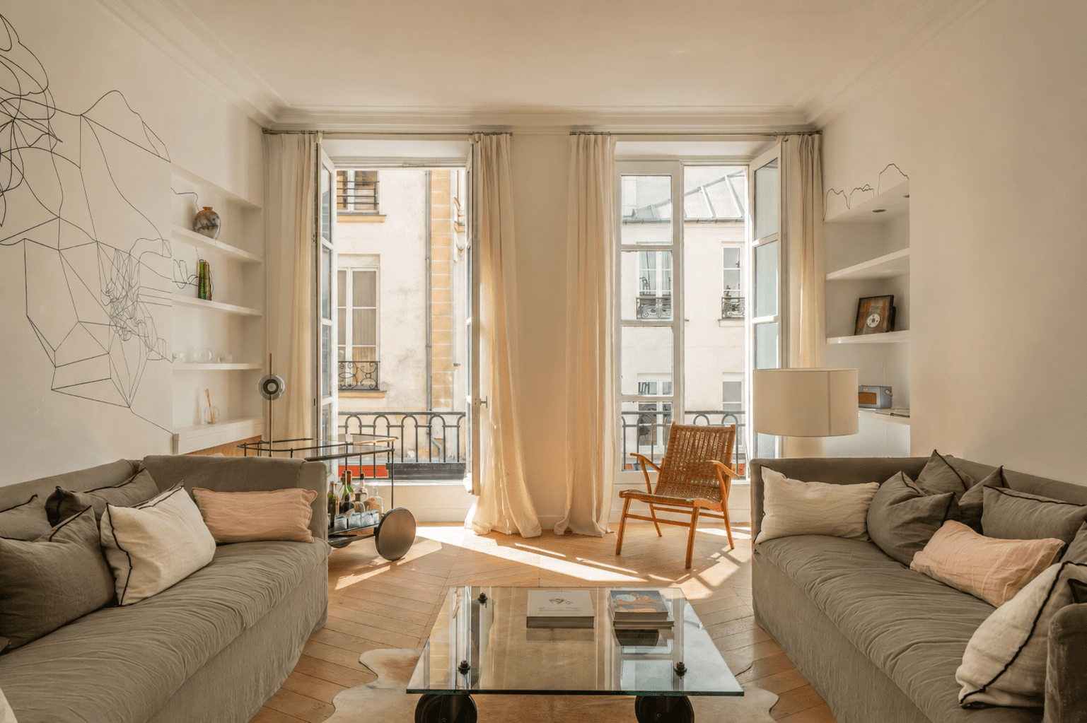 Salon élégant dans un appartement à Paris 1 Saint-Honoré avec parquet point de Hongrie, grandes fenêtres et décoration contemporaine chaleureuse