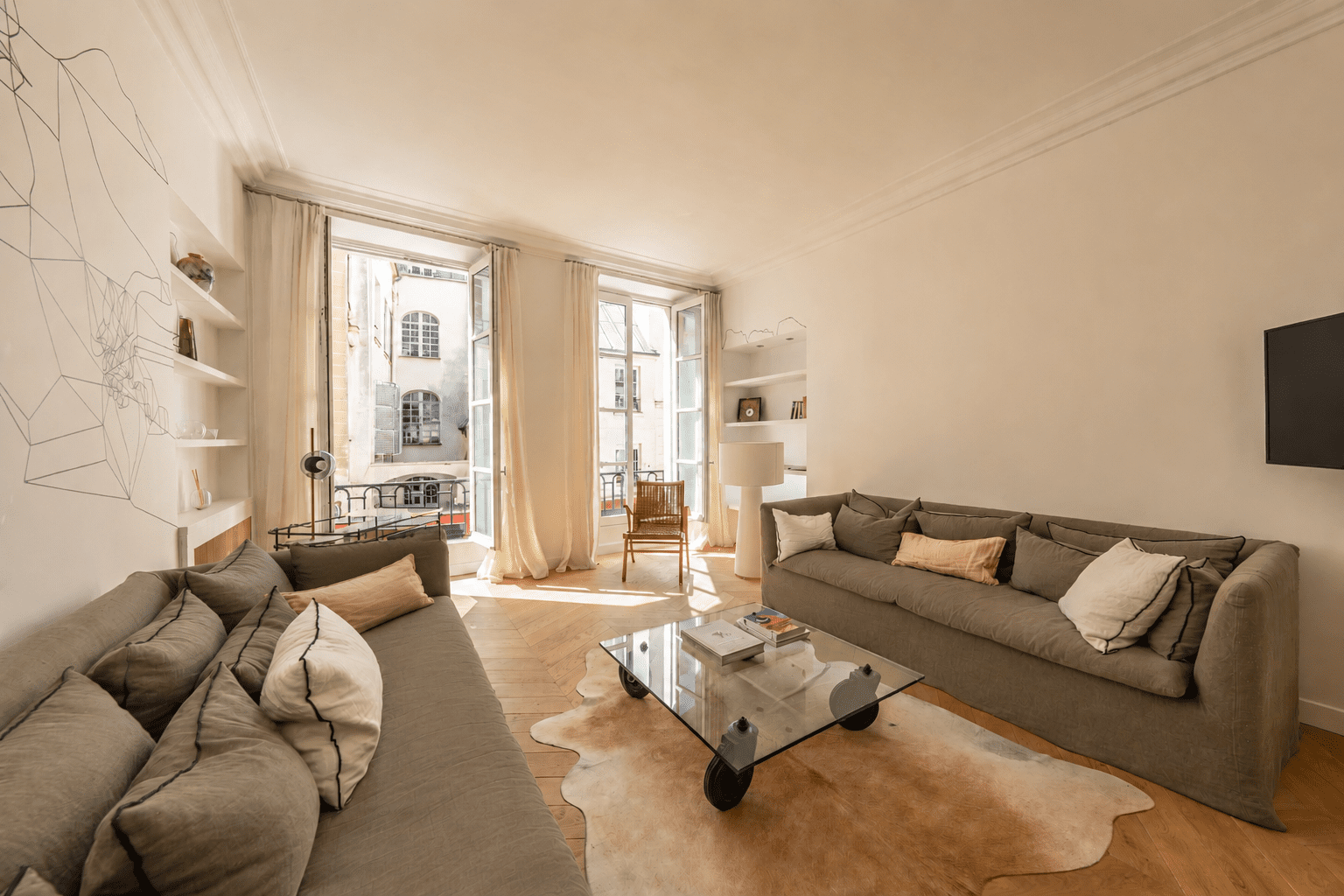 1 790 000 € - Paris 1er • Vendôme / Saint-Honoré • 114 m² avec terrasse Salon lumineux dans un appartement design à Paris 1 Saint-Honoré avec parquet point de Hongrie, grandes fenêtres et mobilier contemporain